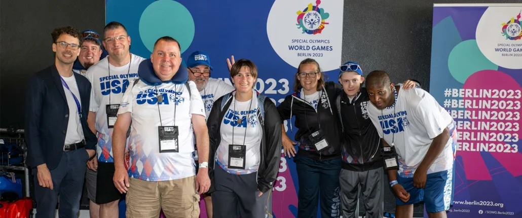 Menschen lächelnd vor Special Olympics Fotowand