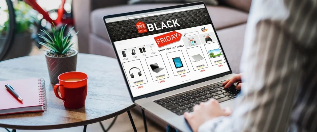 Eine Person sitz am Laptop mit Kaffee und schaut sich Black Friday Angebote an